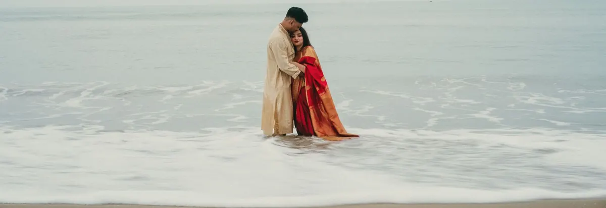 A couple embracing at the edge of the sea on a beach wedding shoot