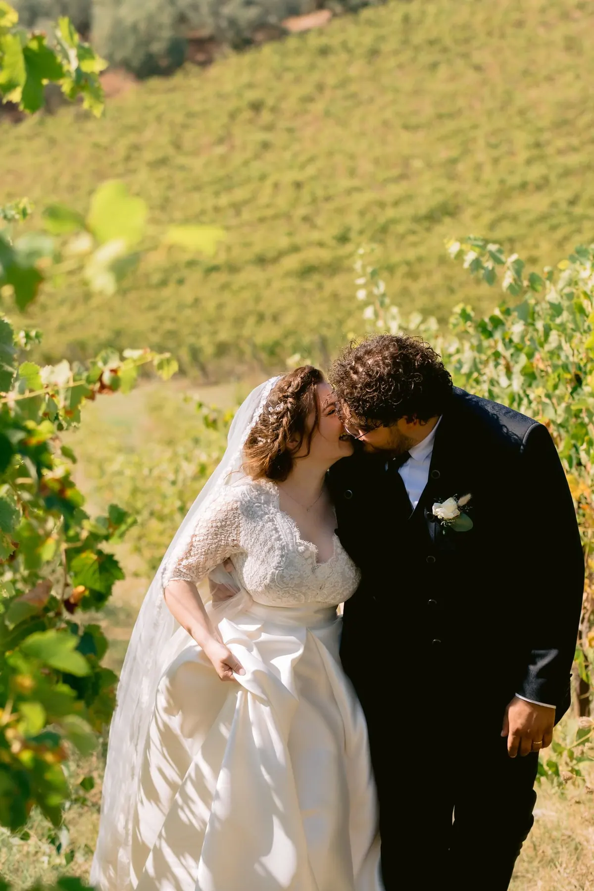 A bride and groom kissing among green vines, edited with a warm golden-hour grade