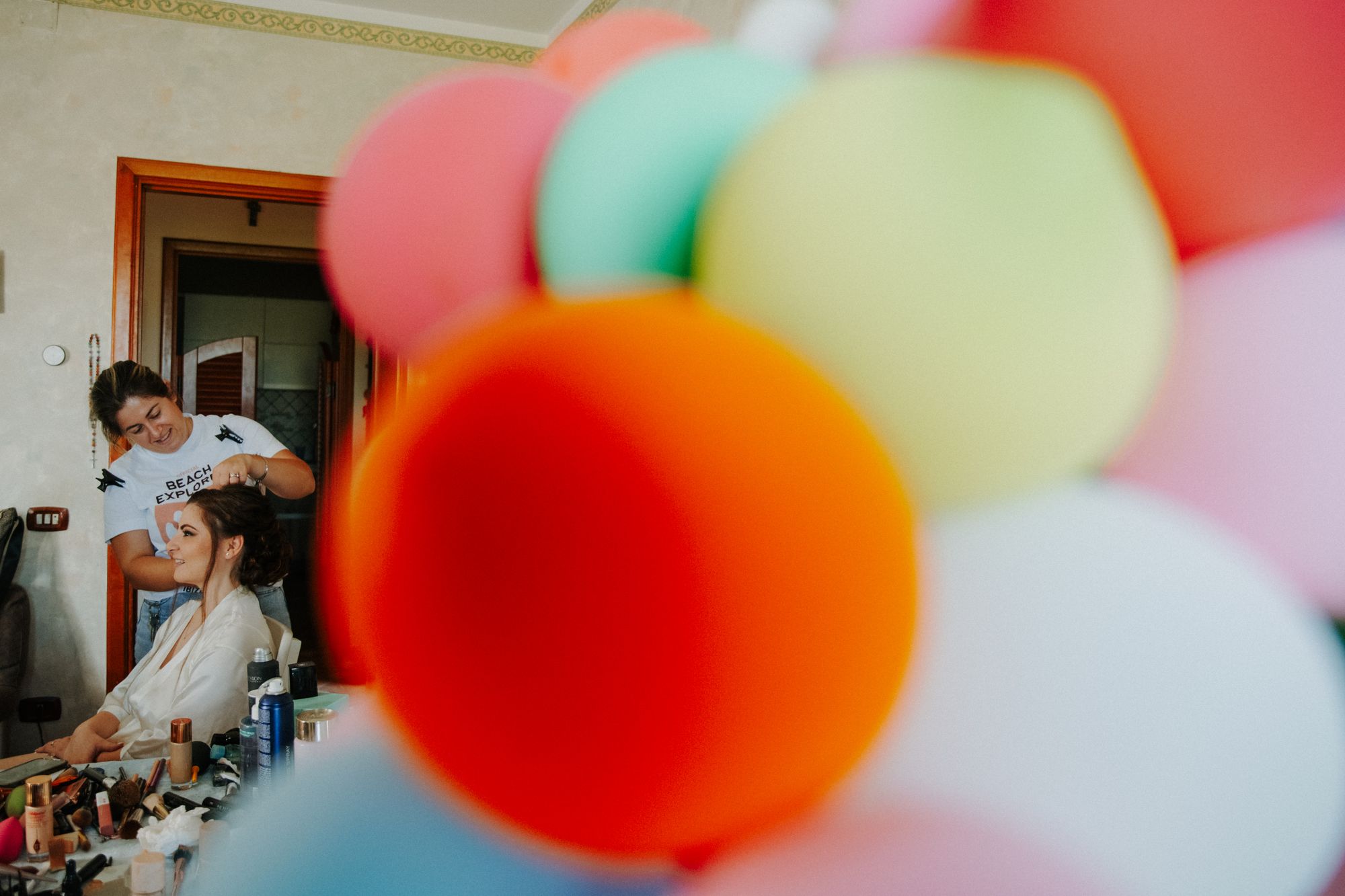 Bright balloons in the foreground of a bride getting ready