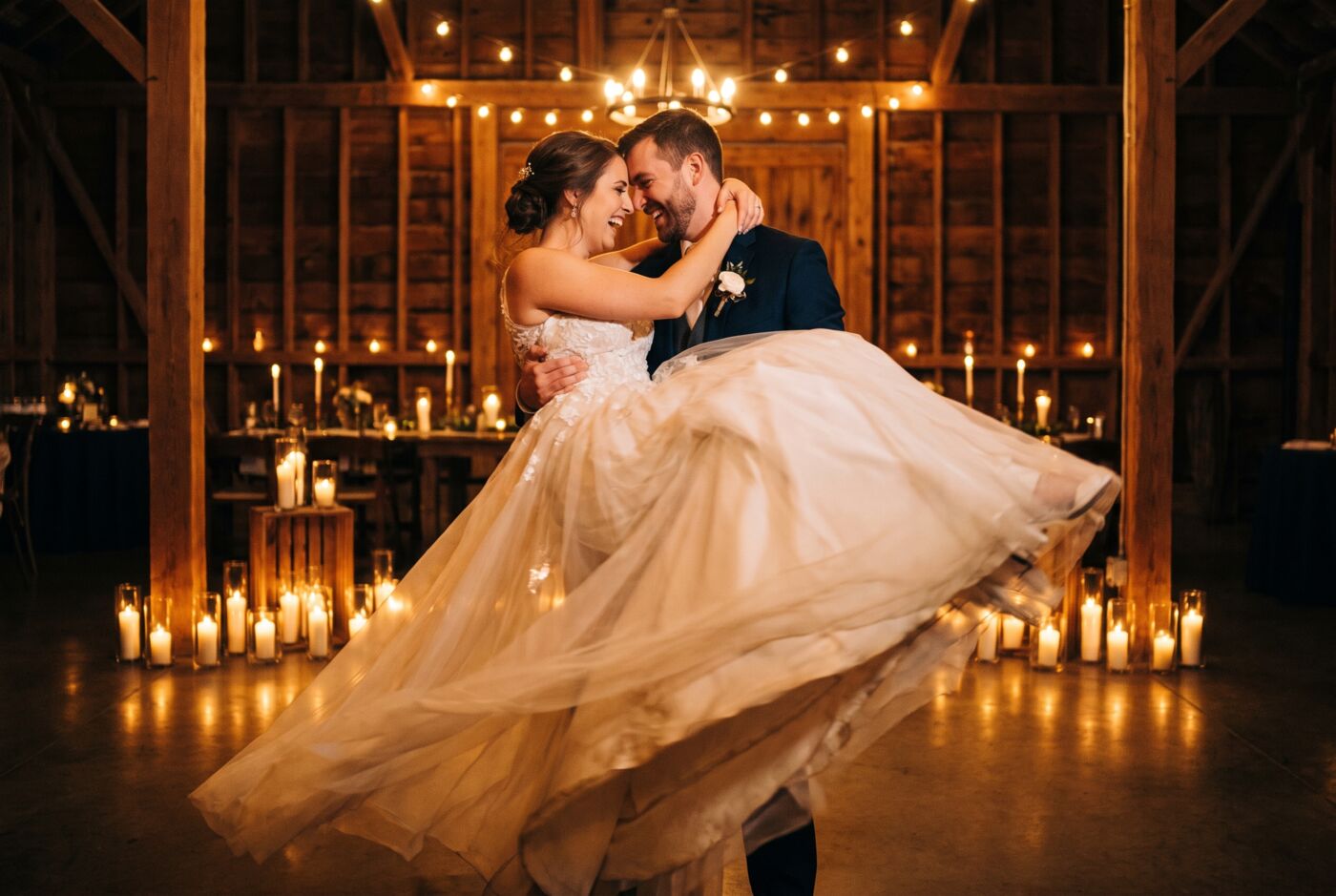 A couple dancing in a candlelit barn, framed for a wedding film